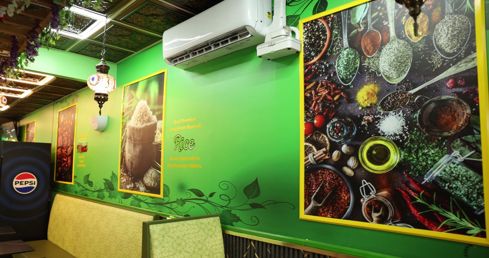 Inside the Gyro King dining room: bright green walls with large yellow-framed photos of spices and rice, a hanging lantern and booth seating